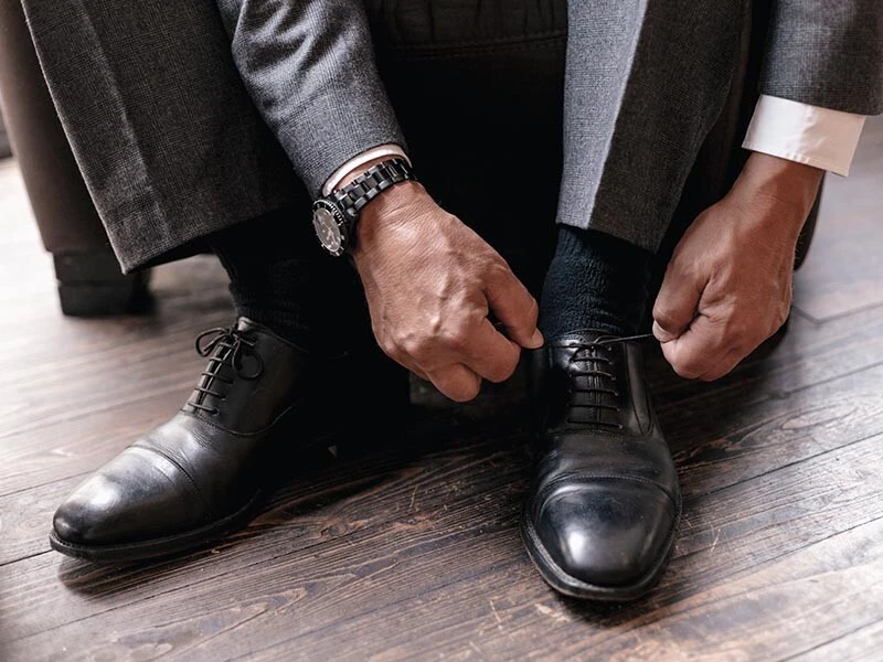 man putting on nice black leather shoes